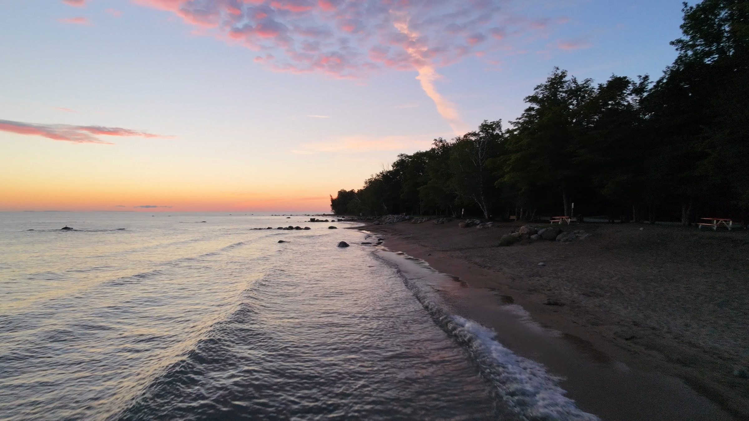 Georgian Bay shoreline at dawn, waves on an empty beach below the trees